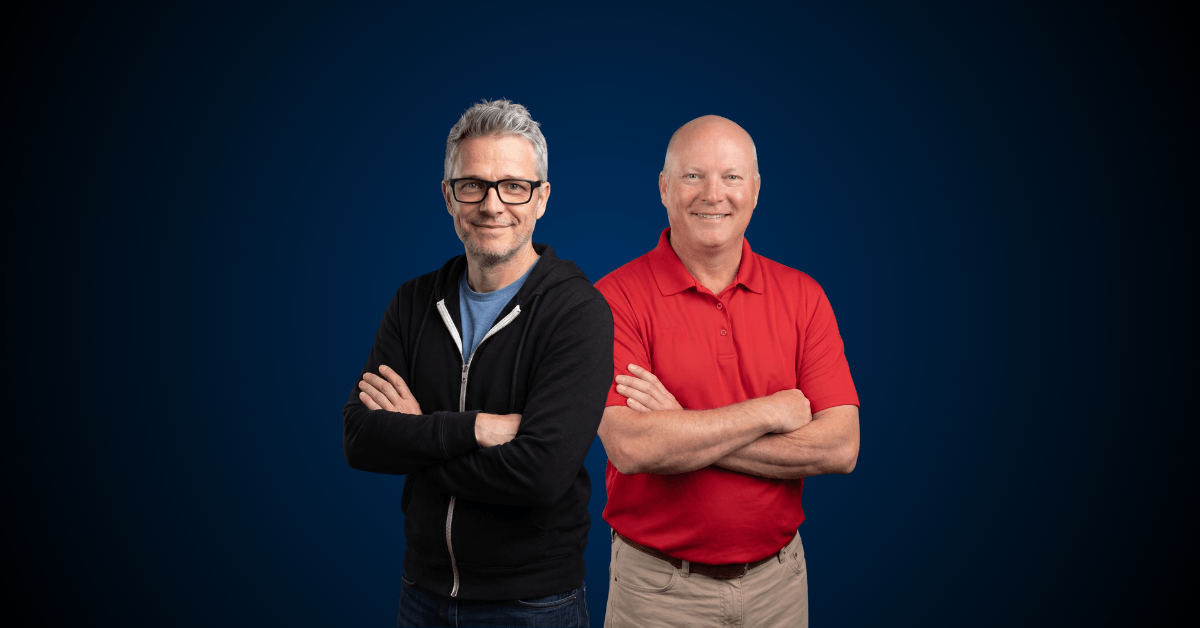 Dave Ginbey and Mike Benton standing side by side with arms crossed, smiling, against a dark blue background.